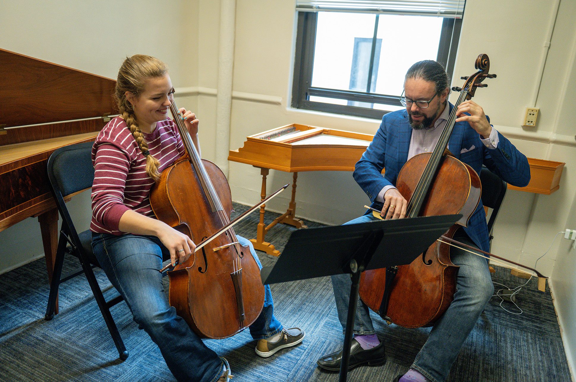 A music lesson with a student and a teacher playing cellos.