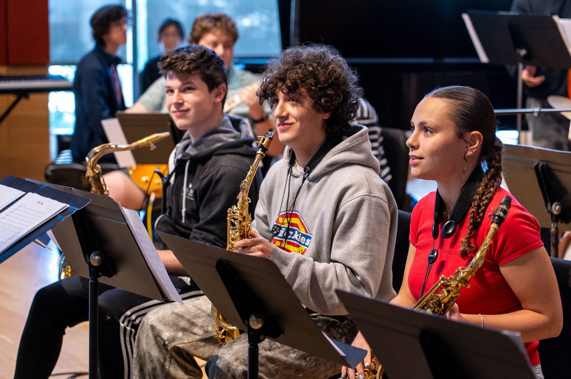 Three students smiling during a jazz orchestra rehearsal.