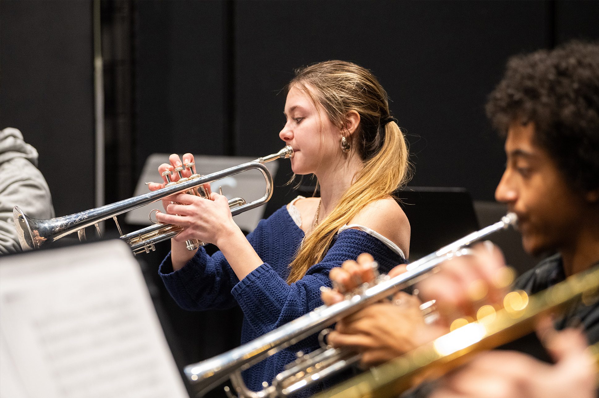 Two young adults playing trumpets.