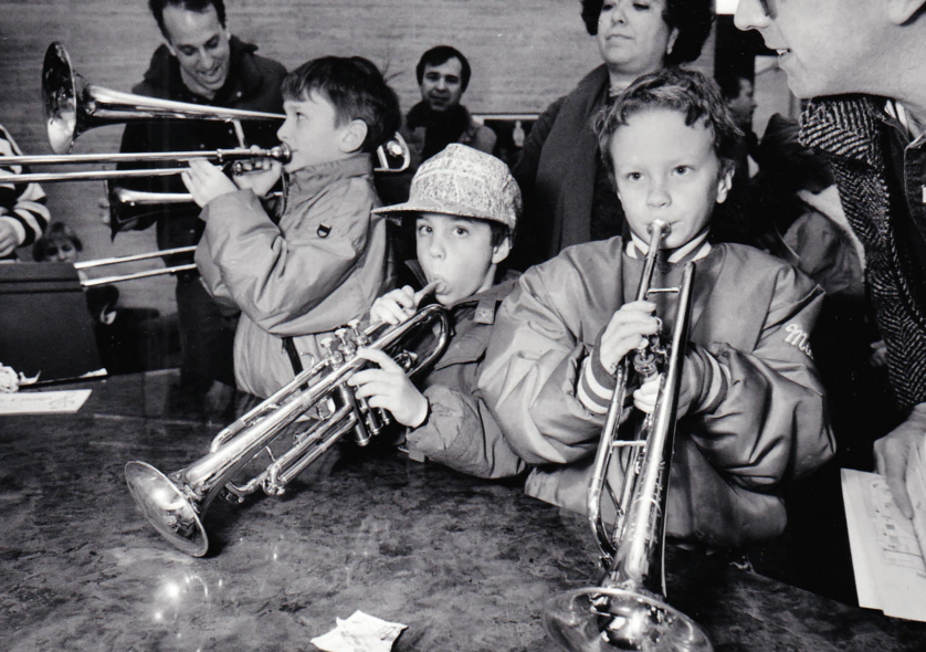  A group of kids trying out some brass instruments at the NEC Instrument Petting Zoo, an event held to introduce children to a variety of musical instruments, 1992. Photo by Jeff Thiebauth.