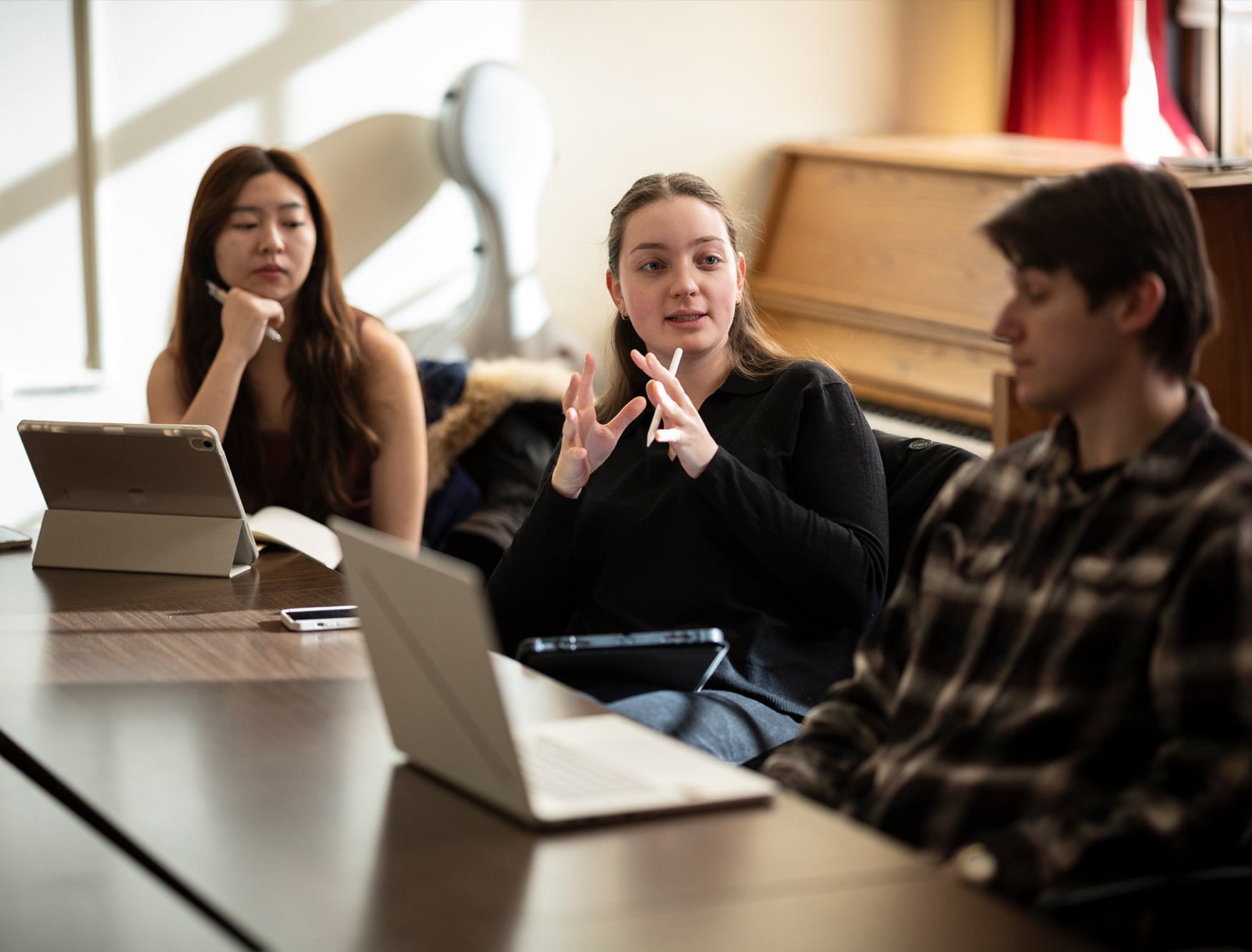 Three students having a discussion in a music classroom.