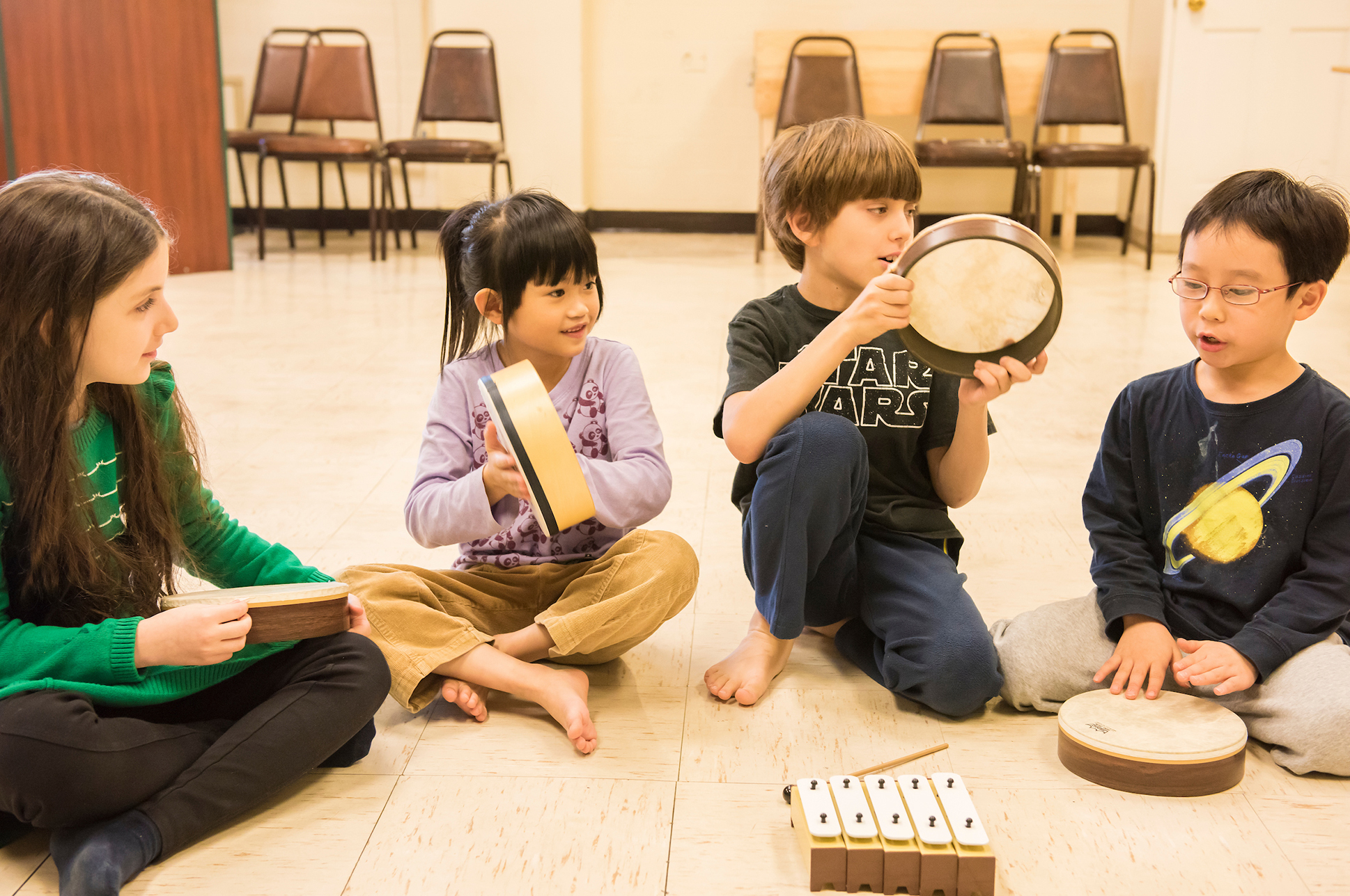 Four children sitting on the floor playing with musical instruments. Four children sitting on the floor playing with musical instruments.