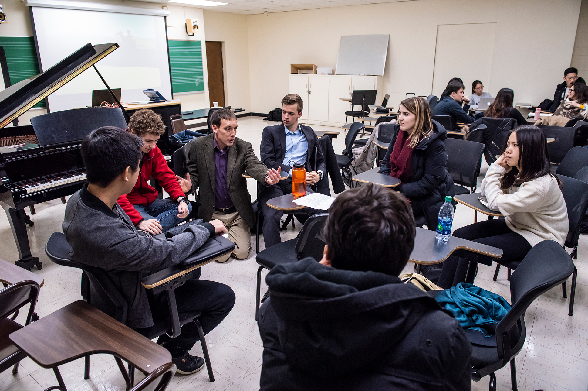 A teacher speaking to a group of students in a classroom.