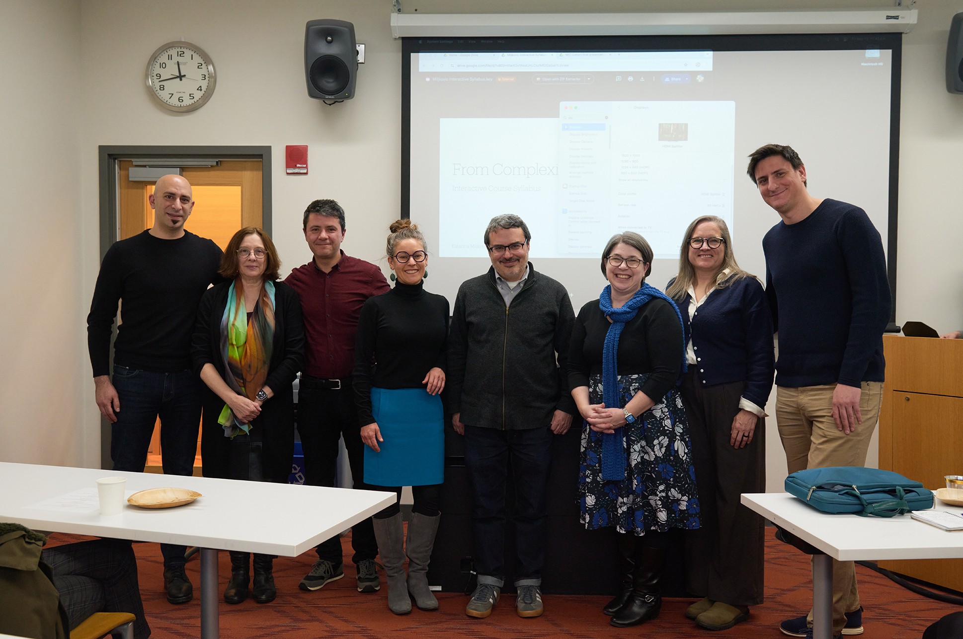 A group of faculty members standing together in a classroom.